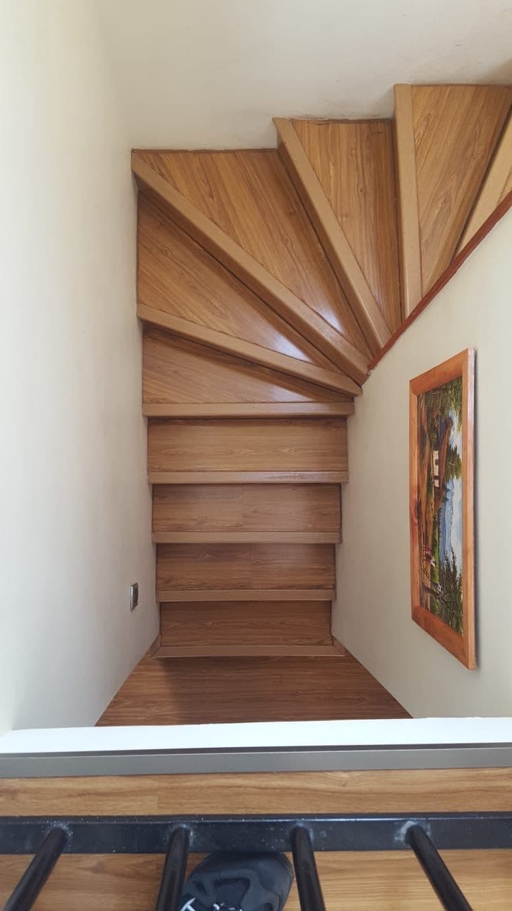 Escalera interior revestida en madera, con peldaños en abanico