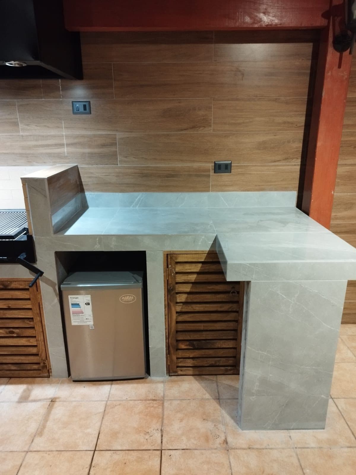 Mesón de quincho revestido en porcelanato símil mármol con muebles de madera