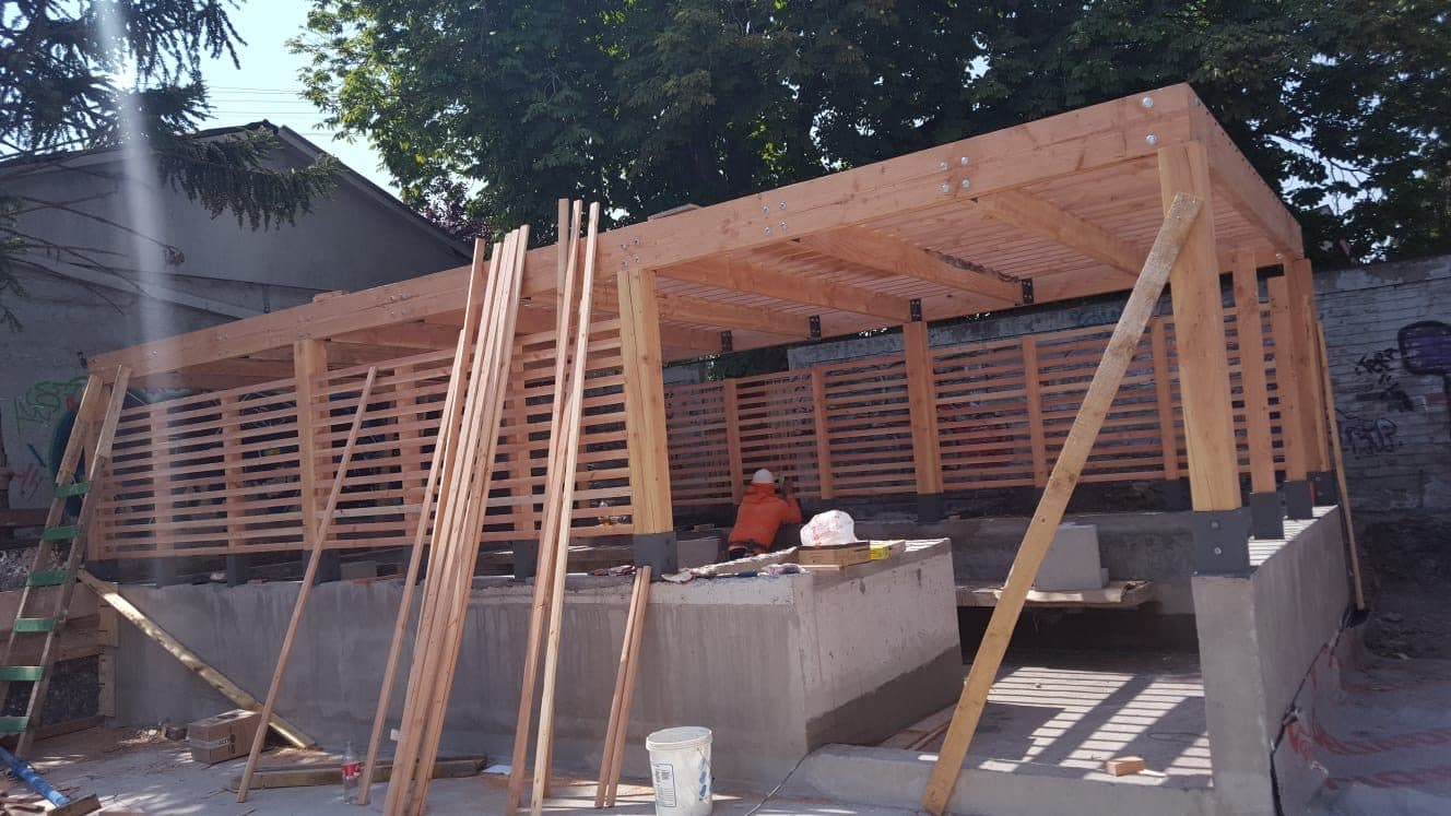 Estructura de pérgola de madera en construcción, con maestro trabajando bajo el techo