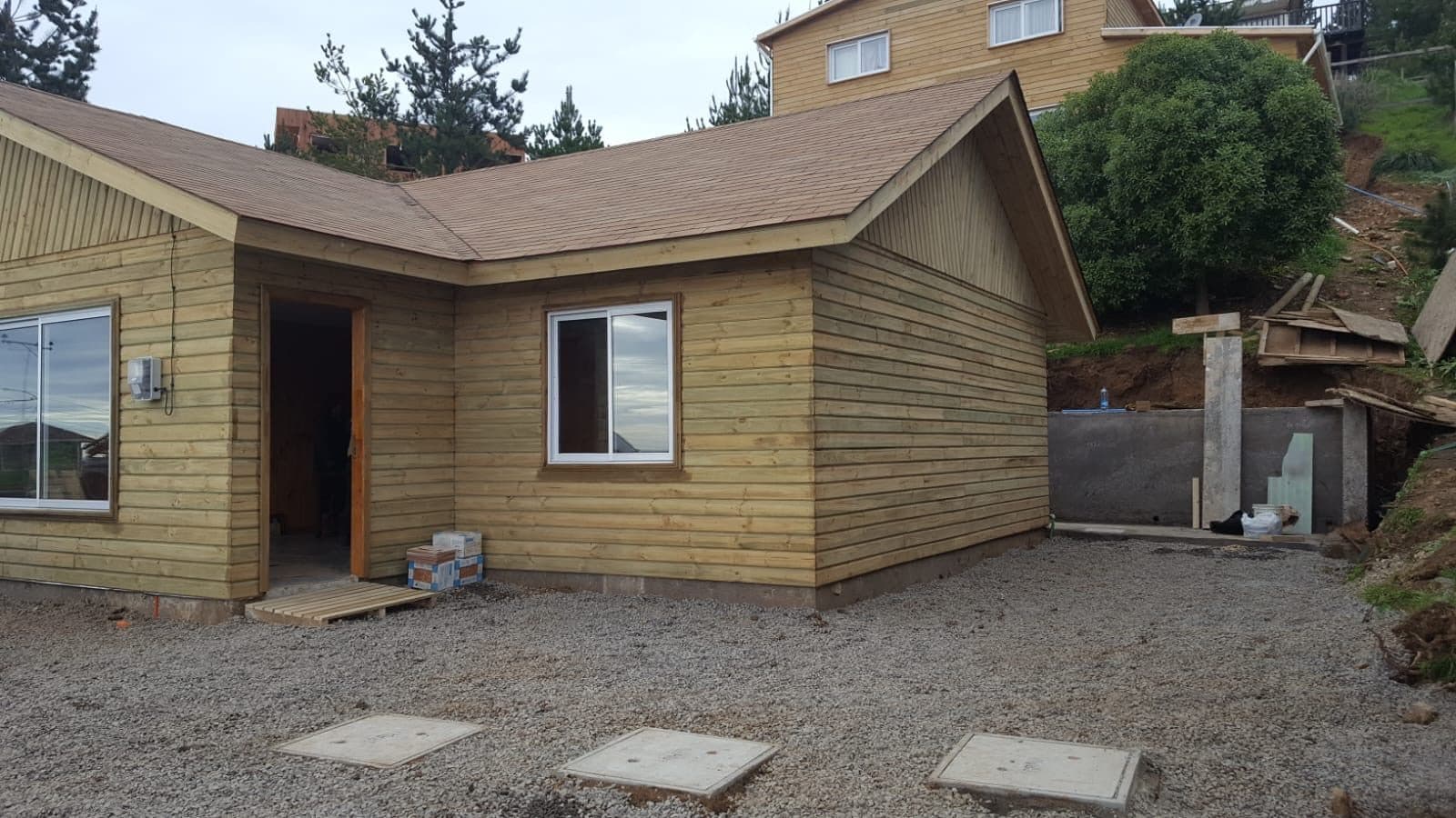 Vivienda revestida en madera con techumbre terminada, en etapa final de obra